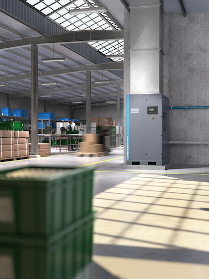 A rendering of a compressor installed against a wall in a warehouse, with racking and packing stations beyond.