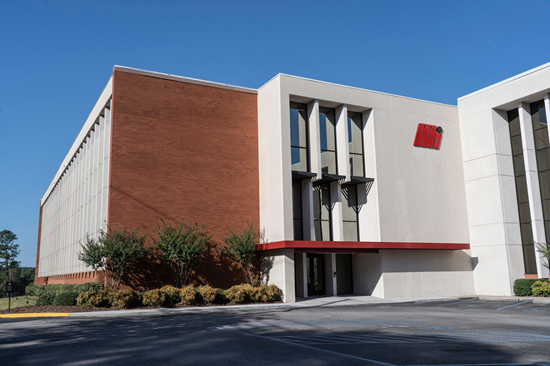 A large brick and concrete office building with a red canopy over the entrance.