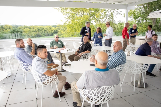 Delegates talking in groups at an outdoor terrace reception.