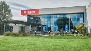 A modern glass-fronted Bobcat building with outdoor seating and parasols.