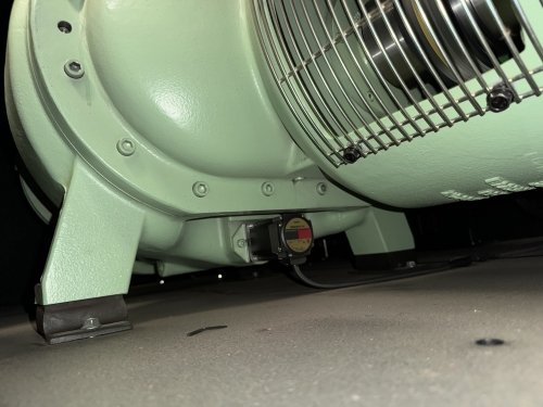Close-up beneath a compressor showing an electronic spiral valve actuator on the airend casing.
