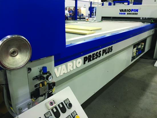 A Vario Press Plus panel press on a trade show floor, with its pneumatic controls at the operator end.