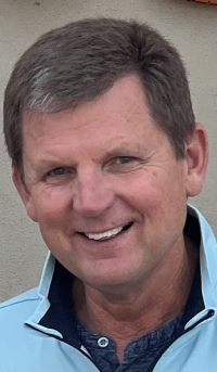 A man in a light blue polo shirt photographed outdoors.