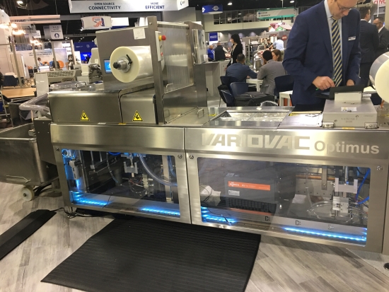 A Variovac thermoforming packaging machine on a trade show floor.