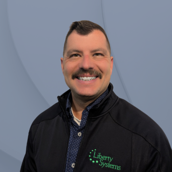 A man in a Liberty Systems jacket photographed against a pale background.