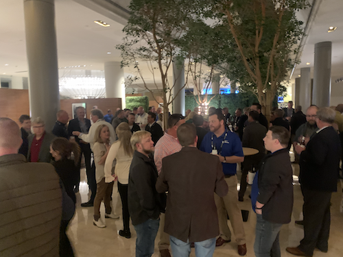 Attendees talking in groups at a conference welcome reception.