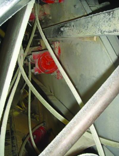 Red pneumatic vibrators mounted beneath a hopper, seen among structural framing.